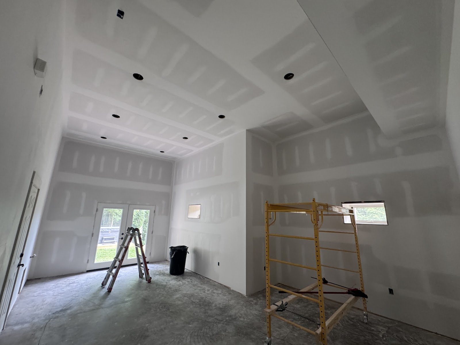 Newly finished drywall walls and tray ceiling in a large room before paint
