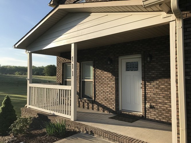 The same front porch with freshly painted light-colored columns, railings and trim