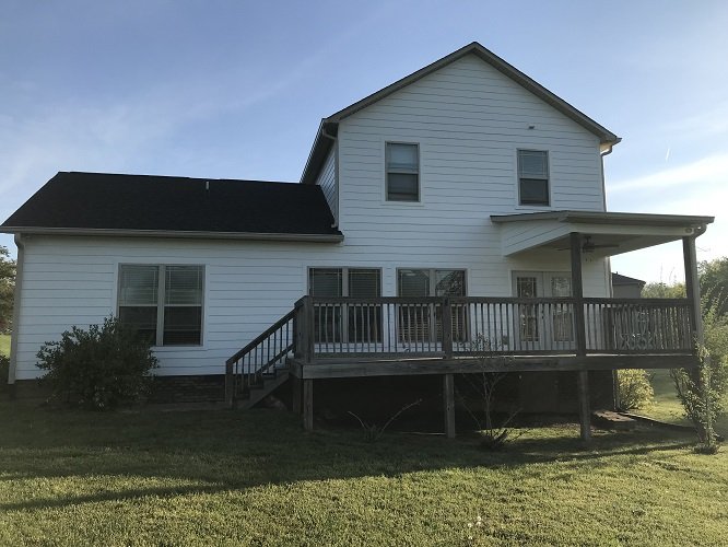 The same two-story house with white exterior siding after repainting