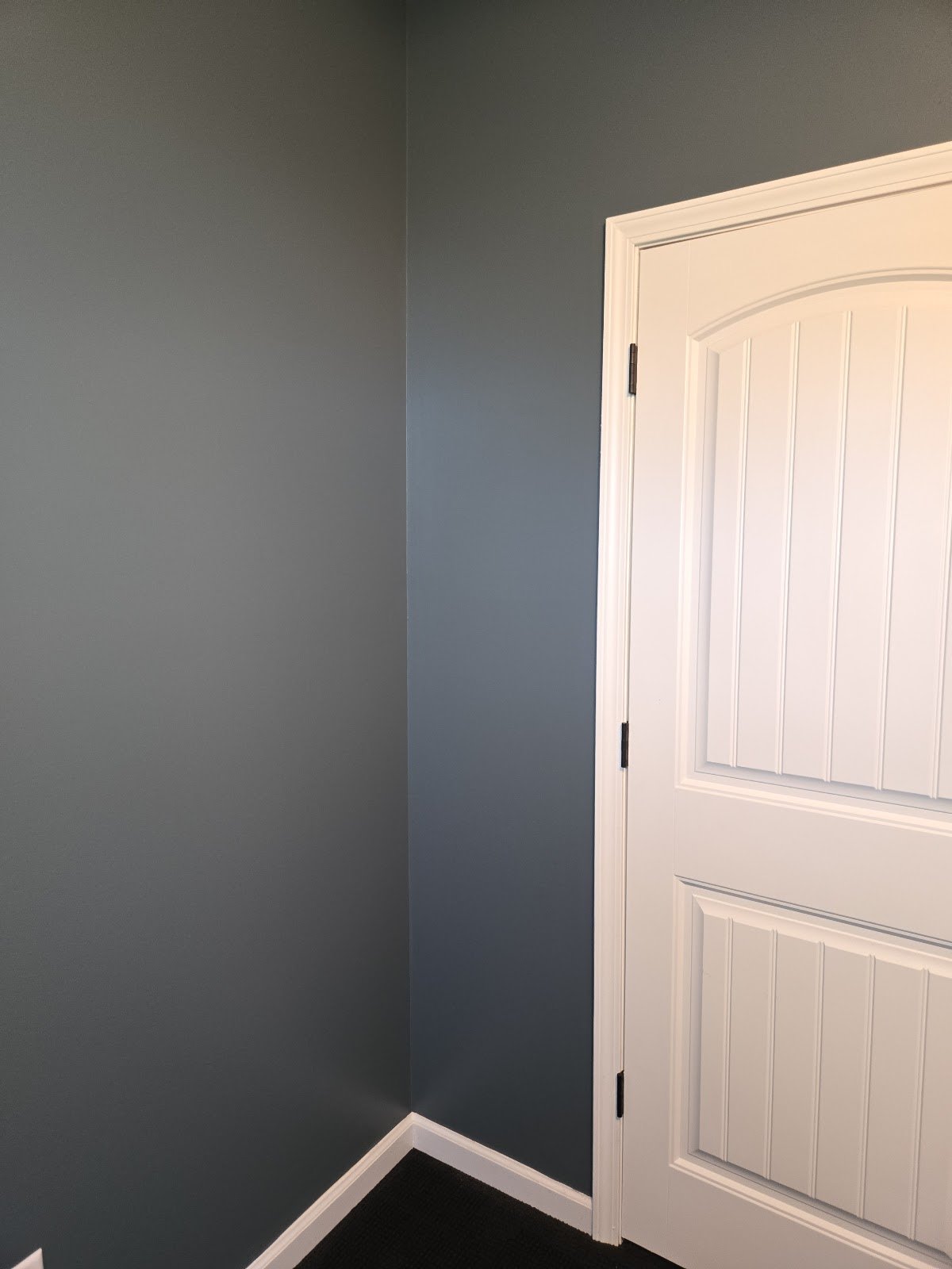 Freshly painted gray interior walls with white door and trim after drywall repair